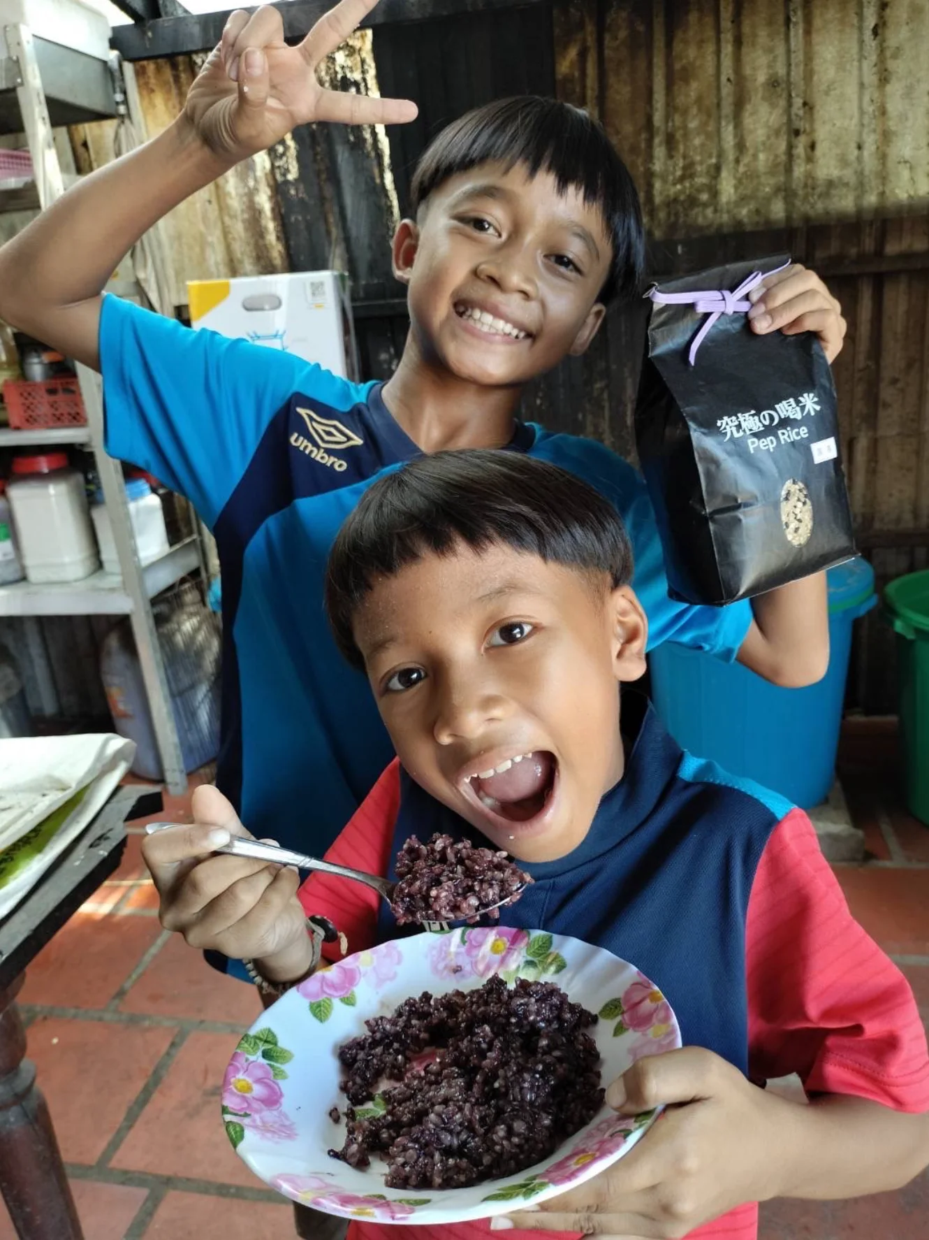 喝米の袋を掲げて笑うカンボジアの子どもたち