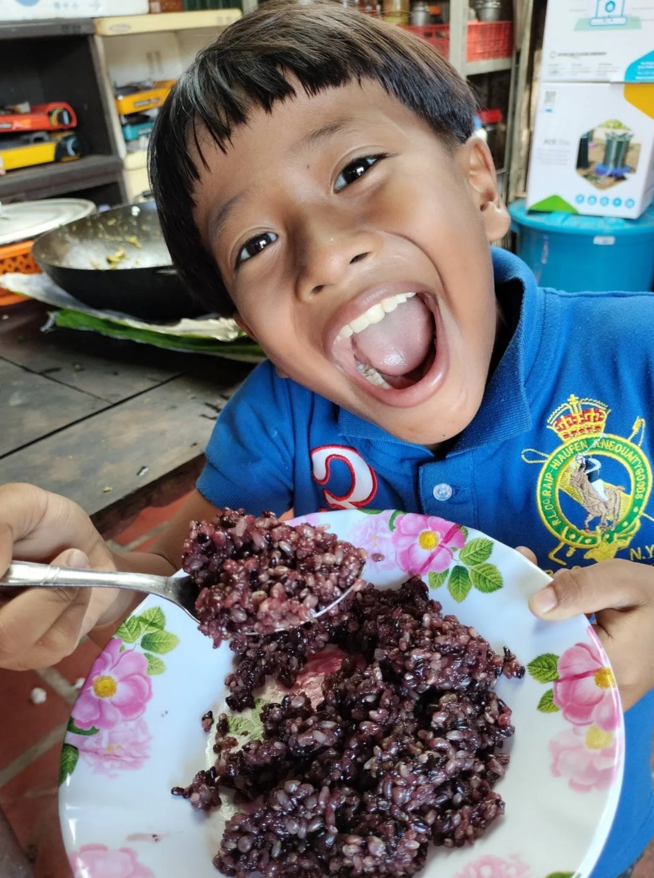 皿に盛った喝米を口いっぱいに頬張るカンボジアの子ども
