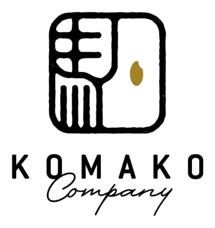 KOMAKO Company（株式会社駒子）のロゴ。手彫りの落款の中に「駒」を崩した線画があり、右上に金の米粒がひとつ置かれている
