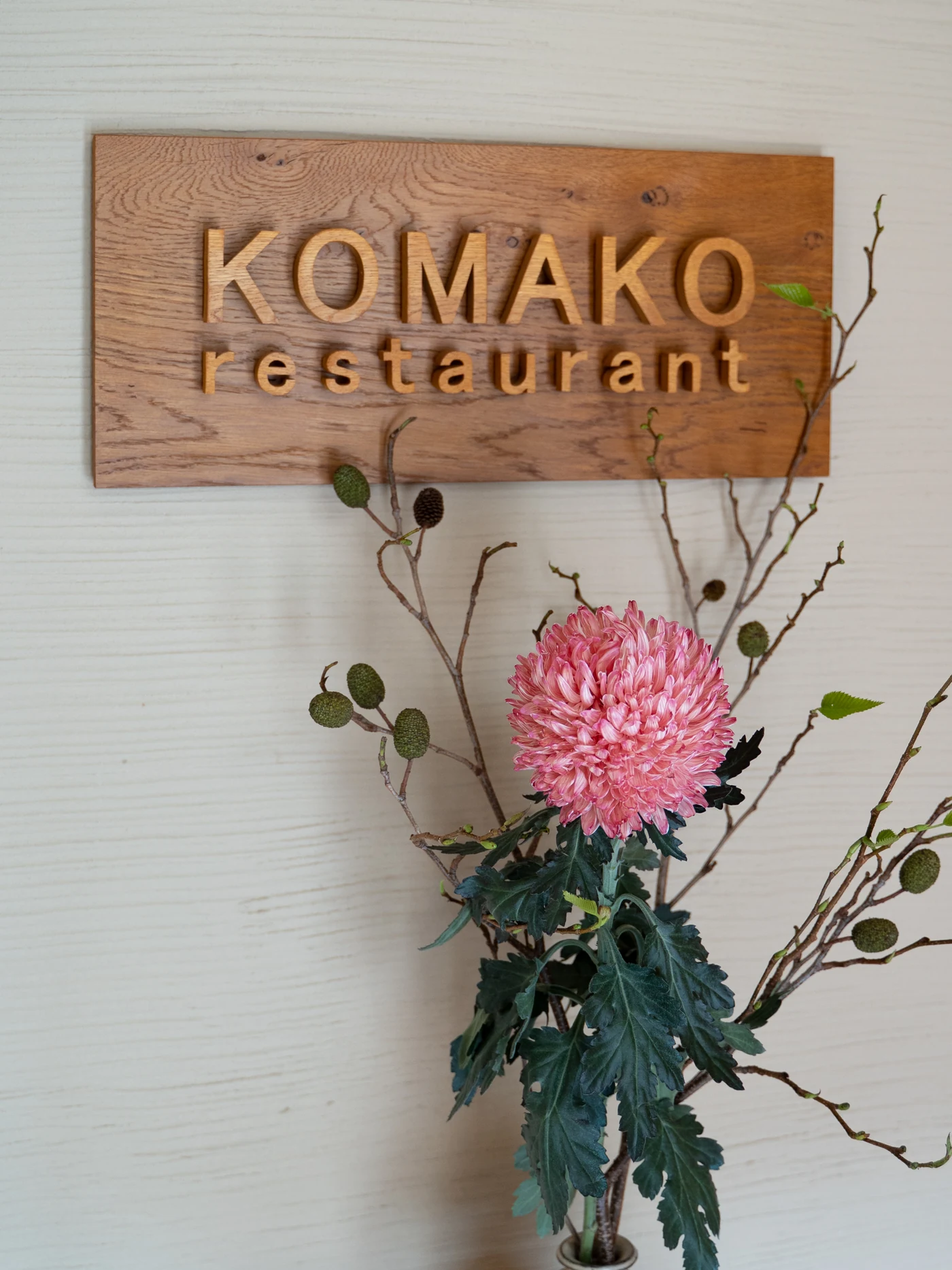 駒子レストランの木の看板。下の一輪挿しに季節の花が生けてある