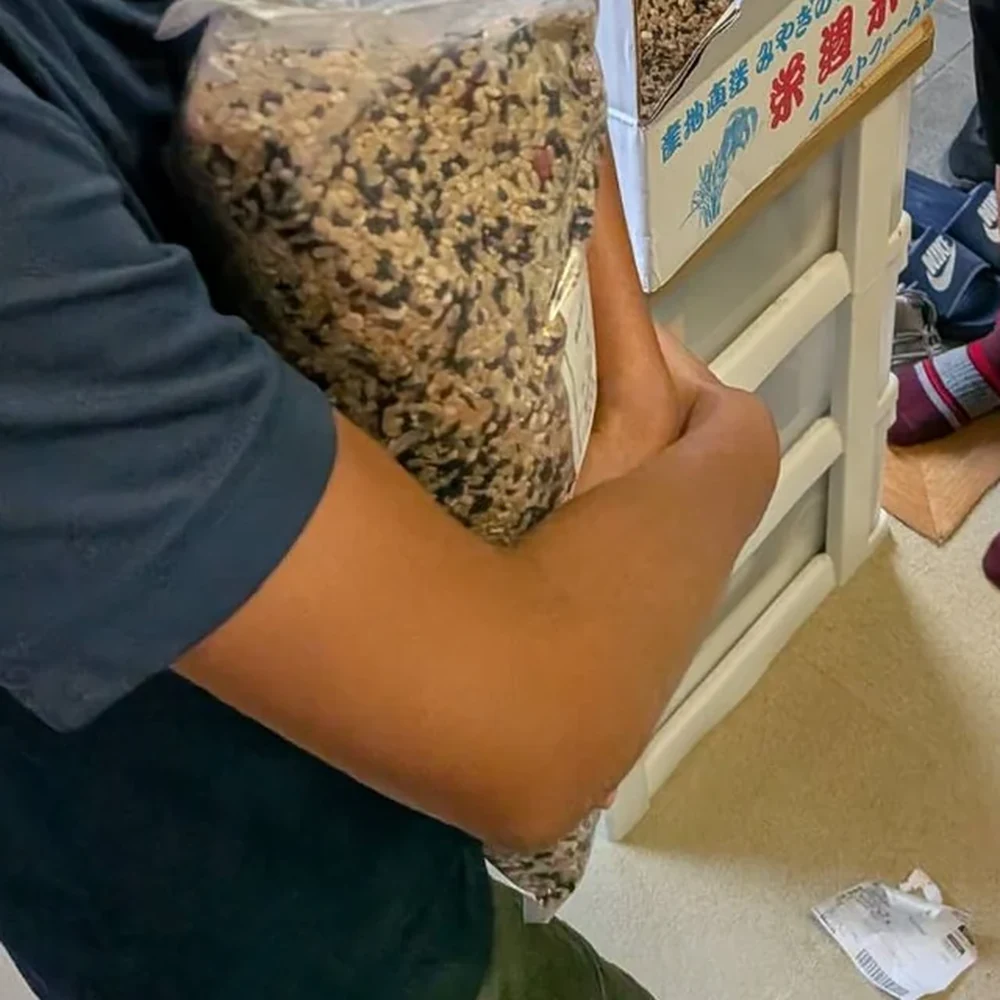 届いた箱から取り出した究極の喝米の袋を、腕に抱える子ども