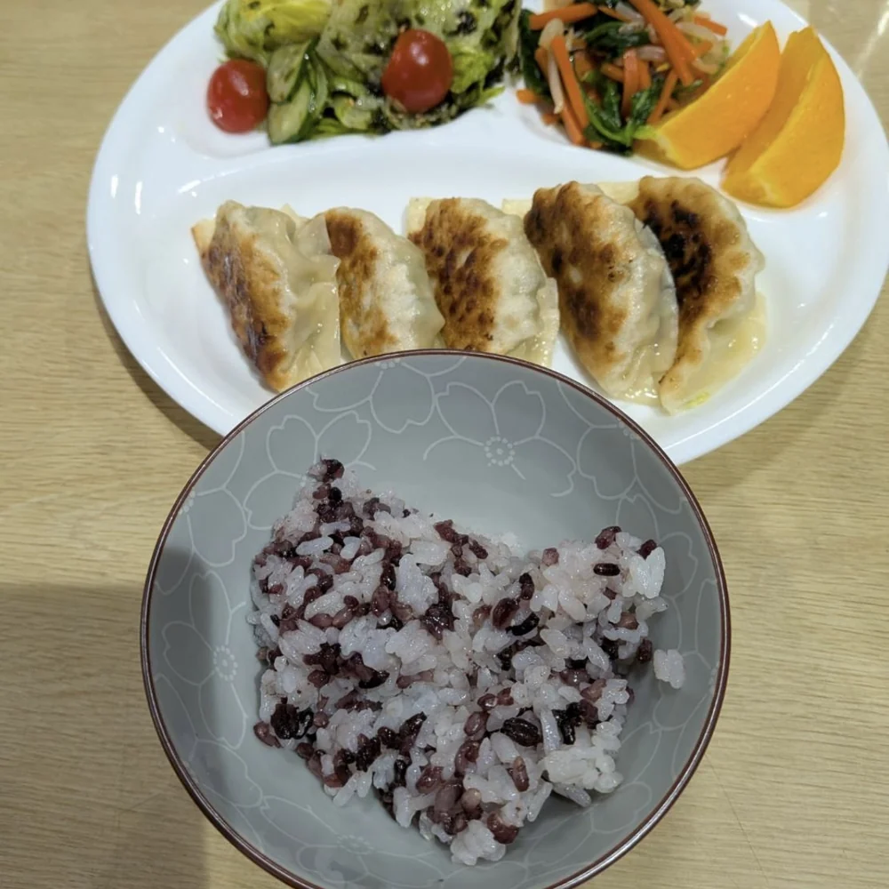 学園の給食。焼き餃子とサラダの皿に、白米と混ぜ合わせた喝米ごはん